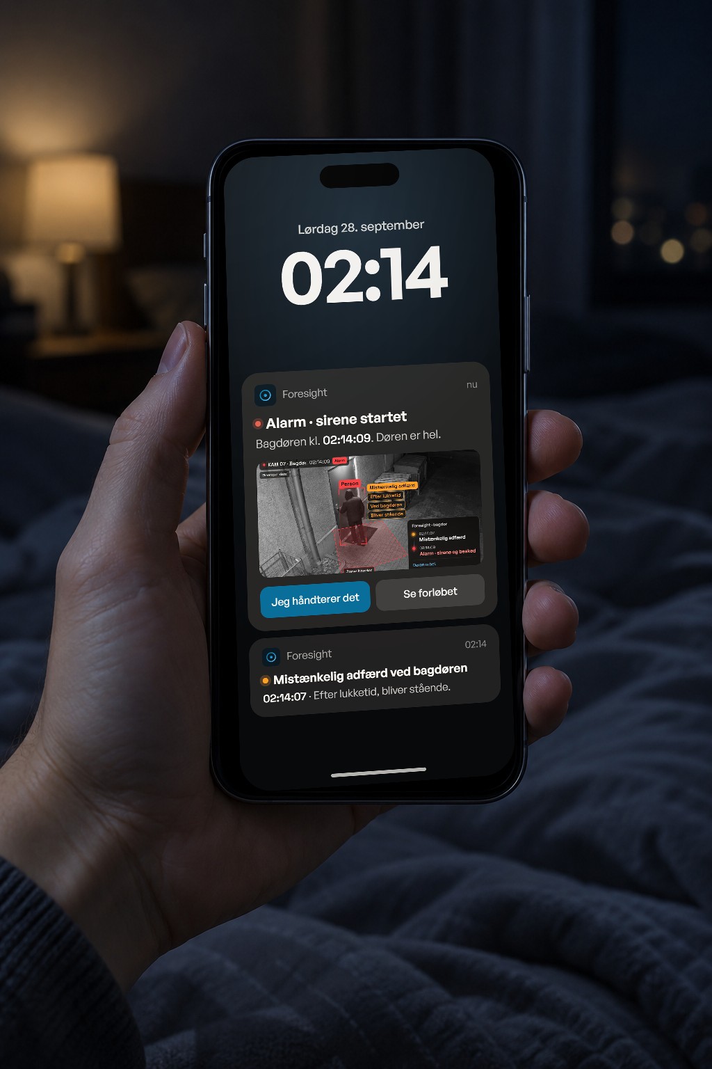 En hånd holder en telefon om natten. Låseskærmen viser to beskeder fra Foresight: mistænkelig adfærd ved bagdøren kl. 02:14:07 og derefter alarm, sirenen er startet kl. 02:14:09, med et billede fra kameraet.